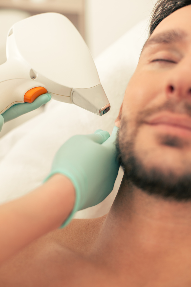 Laser hair removal procedure on the ear of man